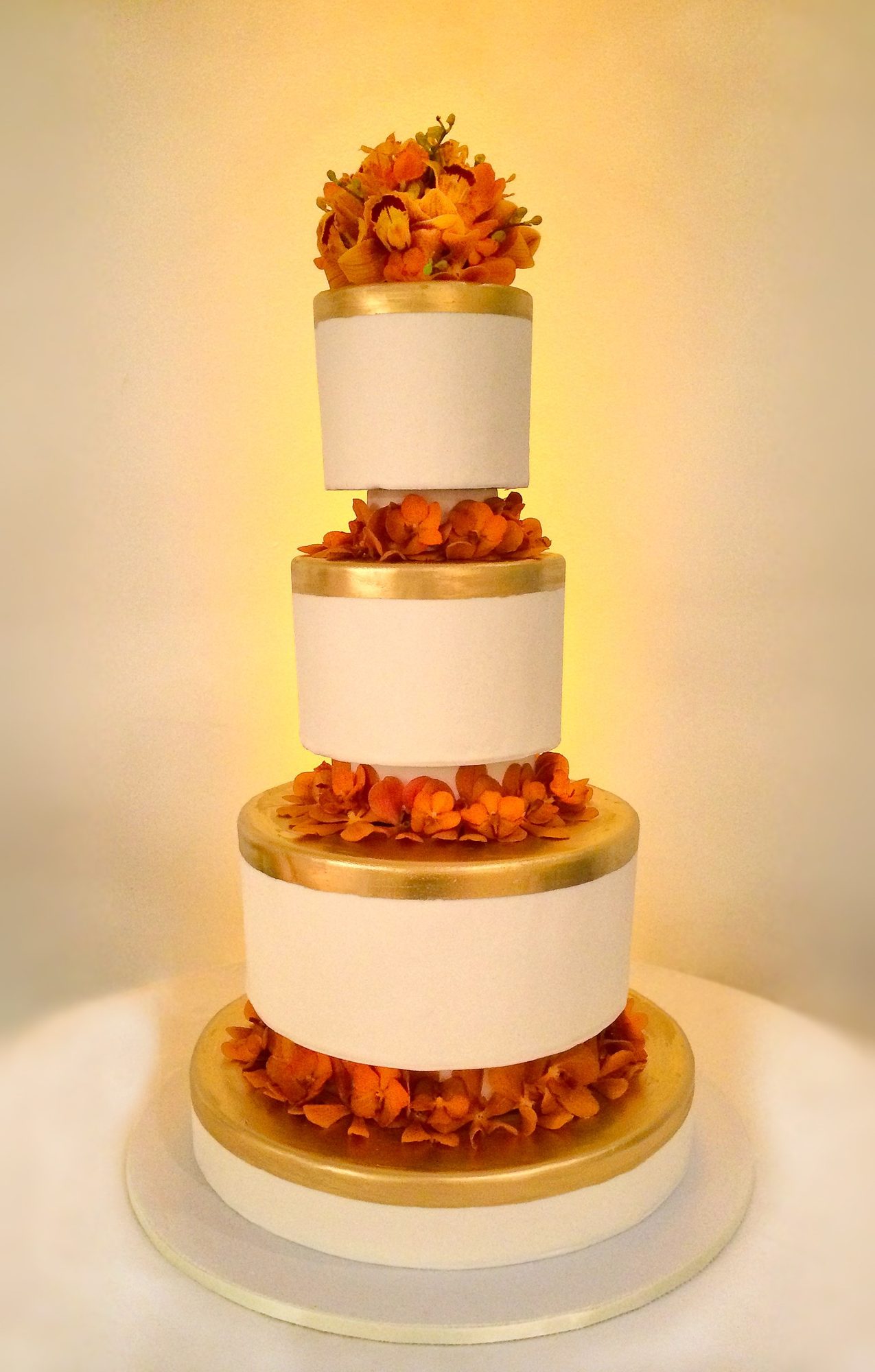 Tiered white and gold cake with orange flowers